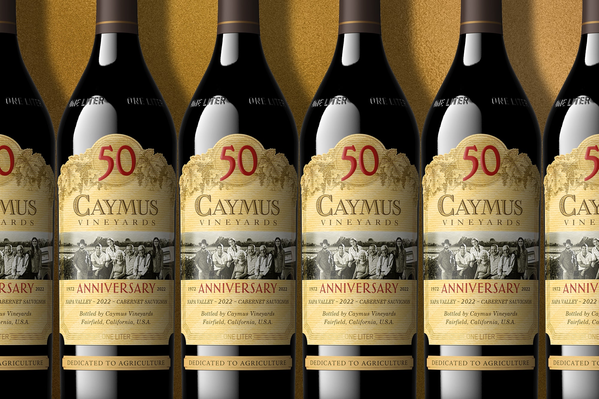 Rows of Caymus Vineyards bottles with a special "50" label in red, celebrating their Anniversary in 2022. The label features a historical image of winemakers and text detailing the wine as a 2022 Cabernet Sauvignon from Napa Valley.